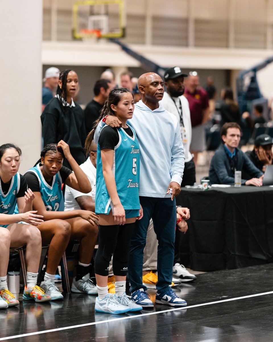 Coach standing with an arm around a Team Taurasi player on the sideline during competition