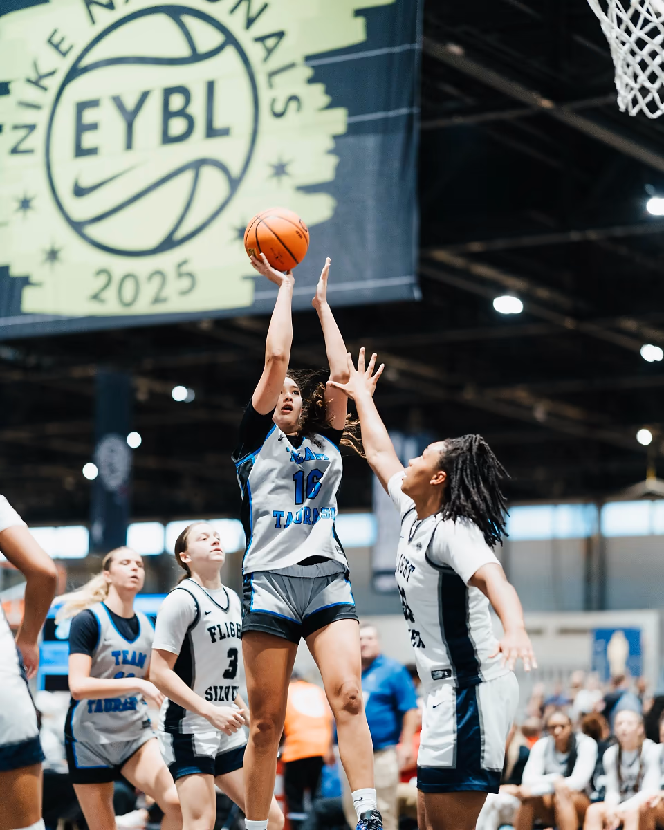 A high school basketball player rises for a jump shot during competition.