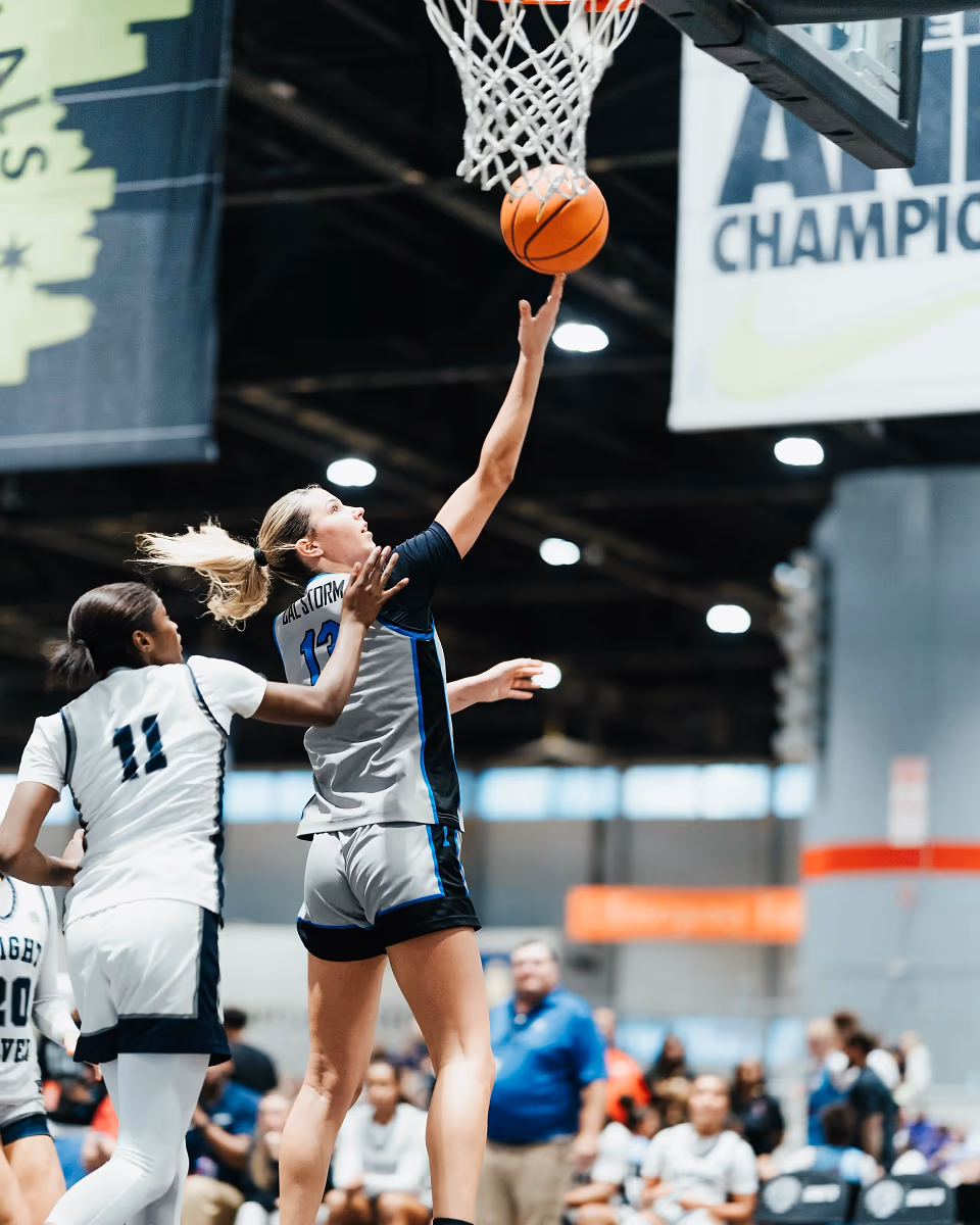 A youth basketball player extends toward the hoop for a layup.